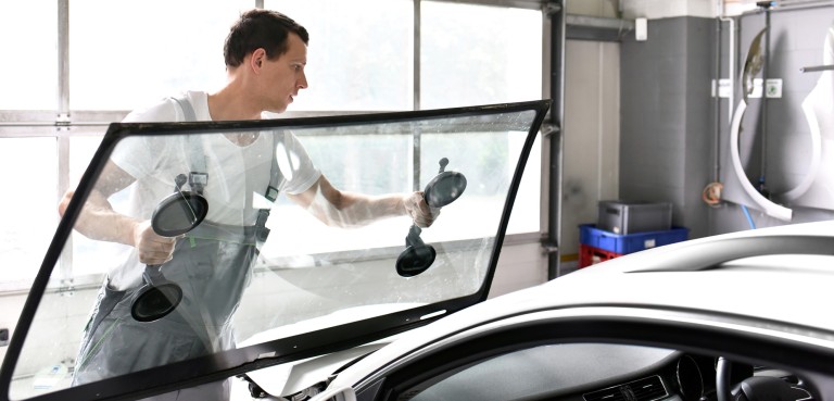 Windscreen Changing Young mechanic in car workshop changing the windscreen of a car